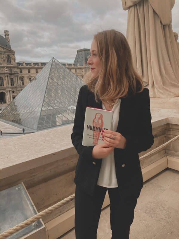 Dr. Stienne with her book, Mummified, posing in front of the Louvre in Paris.